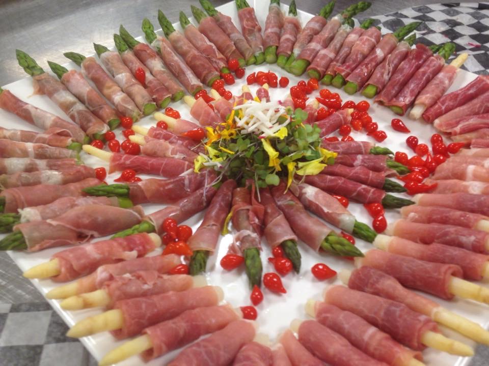 Prosciutto-wrapped asparagus platter with cherry tomatoes and microgreens